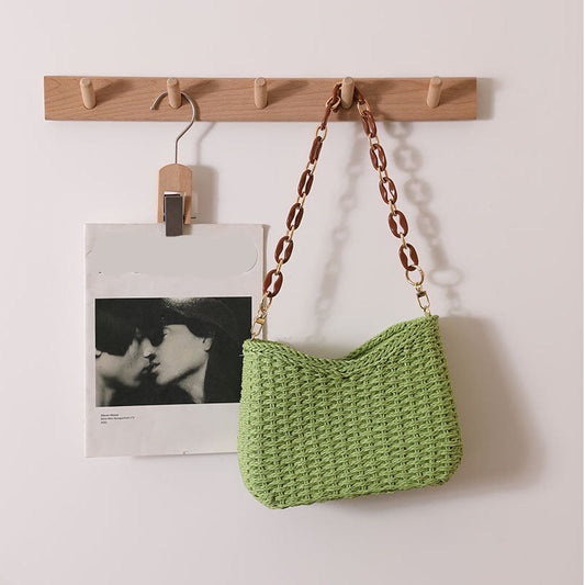 Chic woven straw bag with curved shoulder silhouette and statement chain strap, a stylish women's straw bag that works as a resort bag women love for summer outings and vacation styling, straw sling beach bag, wicker purse, resort bag.