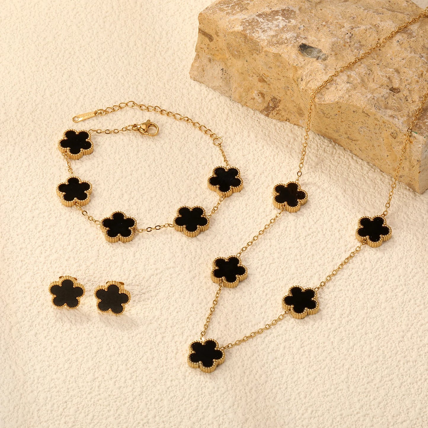 gold clover jewelry set women, clover necklace bracelet earrings set, Matching jewelry set with enamel clover charms, smooth resin texture paired with gold charm jewelry set styling, balanced motif placement, clover necklace bracelet earrings set women, office wear jewelry look, quiet luxury accessories.