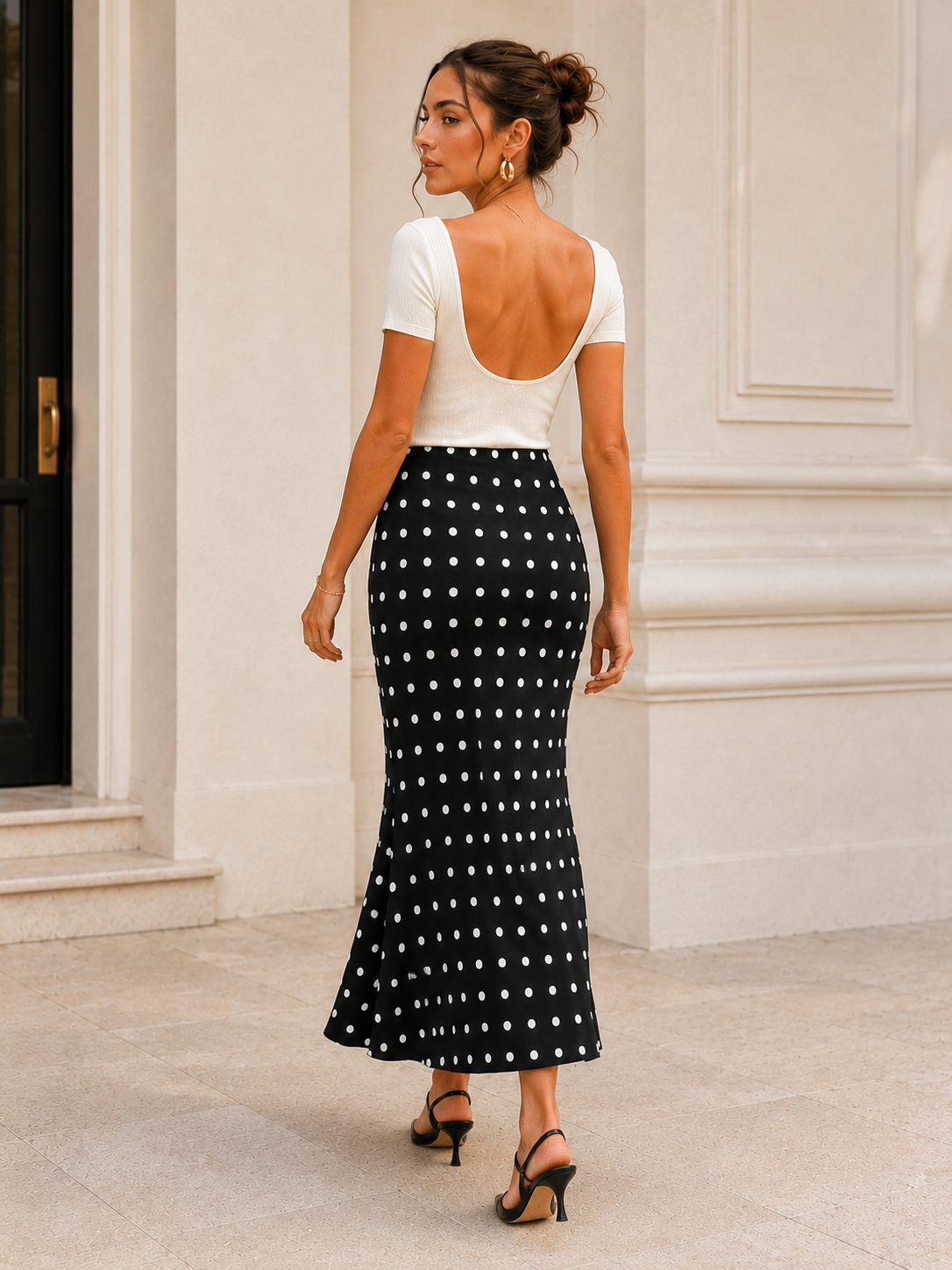 Black polka dot fishtail midi skirt with a fitted upper silhouette and flowing flared hem, styled as a feminine statement skirt for an old money-inspired monochrome outfit with polished appeal.