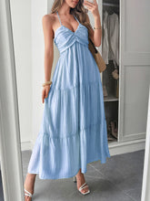 Load image into Gallery viewer, Woman lounging in a tiered maxi dress with halterneck straps relaxed, feminine, and perfect for tropical holidays. With Ruched ruffle tiers and plunging v neckline this summer sundress is perfect for vacation outfit ideas. 