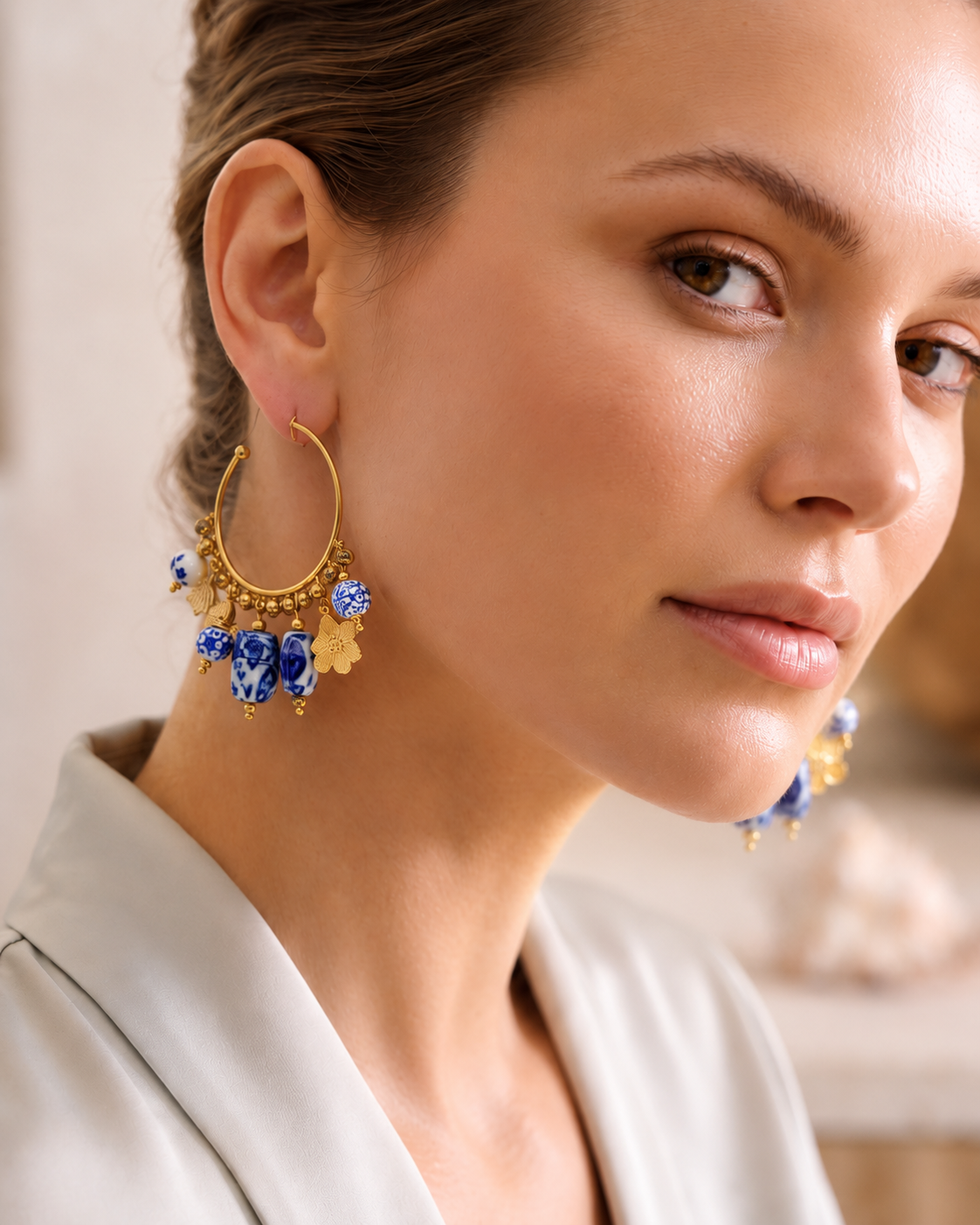 Gold plated ceramic drop earrings with porcelain-inspired blue and white bead details and an open hoop design, crafted as women's statement earrings for versatile day-to-night styling and contemporary jewellery collections.