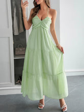 Load image into Gallery viewer, model wearing Halterneck backless maxi dress with tiered ruffles as woman walks toward ocean  ideal for beach weddings or resort wear.