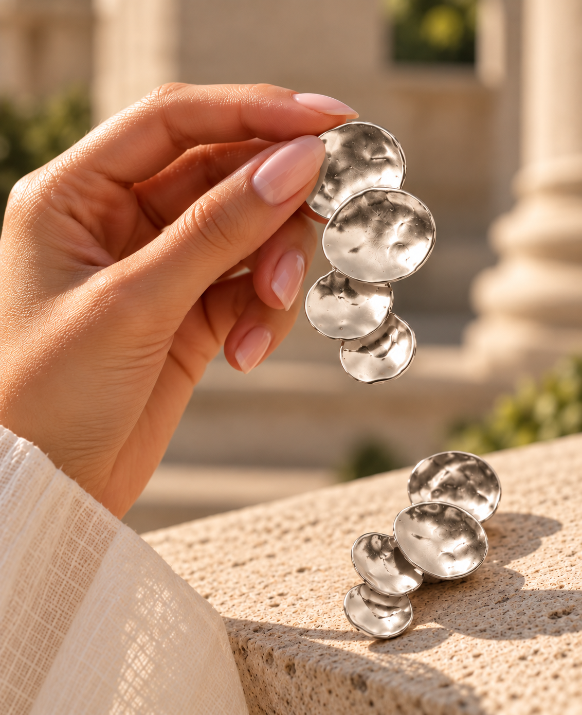 Silver hammered dangle earrings with a long vertical silhouette, layered circular discs and an organic light-catching surface, modern textured statement jewellery for office outfits, evening plans and minimalist wardrobes.