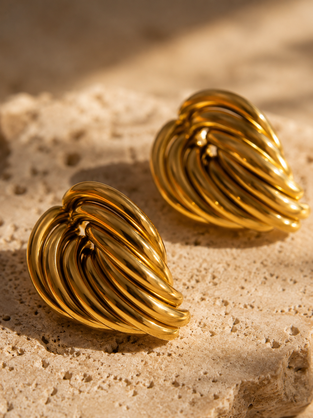 Modern chunky gold stud earrings with a high-shine knot design styled for quiet luxury and contemporary fashion.