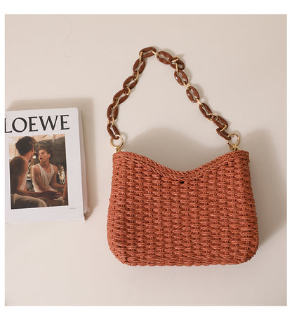 Natural woven straw handbag with structured silhouette and chunky chain strap, a chic women's straw bag perfect for resort wear outfits and effortless casual summer purse styling.