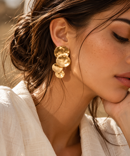 gold drop earrings for women, gold dangle earrings, women’s statement earrings, hammered earrings for women, Gold hammered disc drop earrings for women with an elongated cascading silhouette, overlapping irregular round plates and a reflective textured finish, sculptural statement jewellery for dinner dates, brunch and polished everyday outfits.