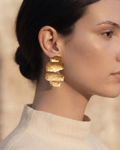 Textured gold statement drop earrings with an abstract sculptural shape and hammered finish, creating a bold contemporary accessory that complements linen outfits, tailored workwear, occasion dresses and minimalist wardrobes.