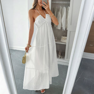 White Boho maxi dress styled with statement earrings and a woven beach bag – perfect for summer travel outfit ideas.