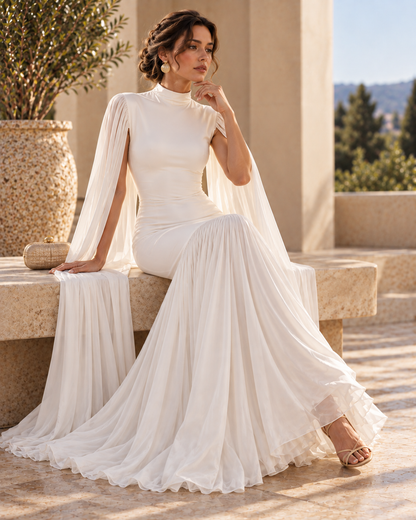 White evening gown for women featuring cape sleeves, fitted waist, high neckline and asymmetrical pleated skirt, creating a graceful floor-length formal dress for weddings, evening receptions and elegant events.