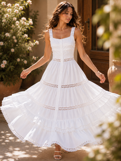 White tiered lace maxi dress with wide lace shoulder straps, scalloped lace tiered hem, a flattering fit and flare silhouette, and covered buttons, styled as a summer wedding guest dress for elegant garden ceremonies and destination celebrations.