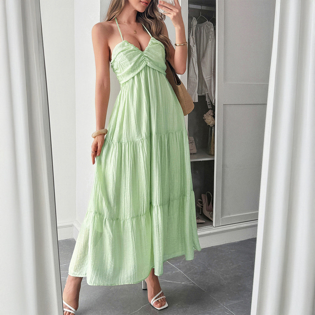 Woman lounging in a Earthy Green tiered maxi dress with halterneck straps relaxed, feminine, and perfect for tropical holidays. With Ruched ruffle tiers and plunging v neckline this summer sundress is perfect for vacation outfit ideas. 