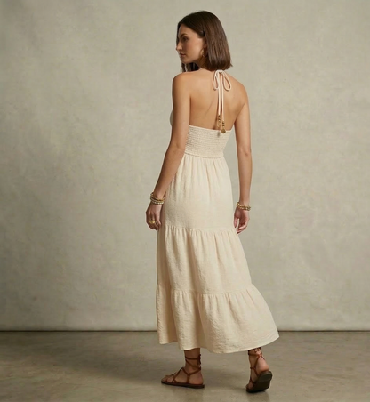 Open back halter tiered maxi in beige lightweight woven fabric, bohemian maxi dress with smocked waistband and tiered skirt silhouette for beach vacation tiered maxi dress looks.