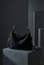 Load image into Gallery viewer, black medium hobo tote bag, medium tote bag, Suede shoulder hobo, roomy slouchy silhouette, removable strap for crossbody wear, commuter work bag for women, travel tote, neutral fall handbag, old money style, casual tote bag, shoulder tote bag, everyday suede tote bag.