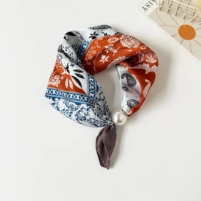 Printed silk-feel neck scarf with an elegant magnetic pearl closure, floral pattern, smooth drape, and lightweight design for sophisticated everyday styling.