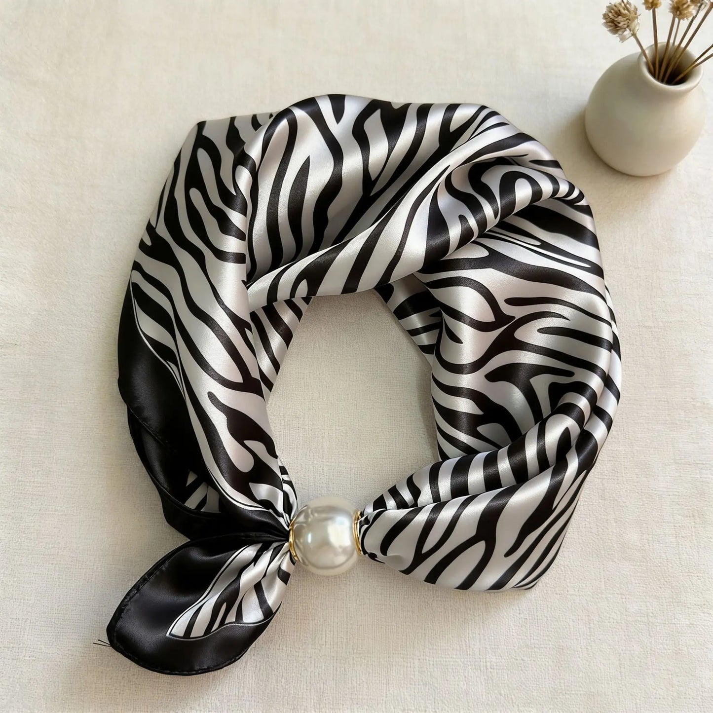 Slim printed faux silk neck scarf featuring a smooth satin finish, botanical-inspired print, and oversized pearl magnetic closure for a refined women's fashion accessory.