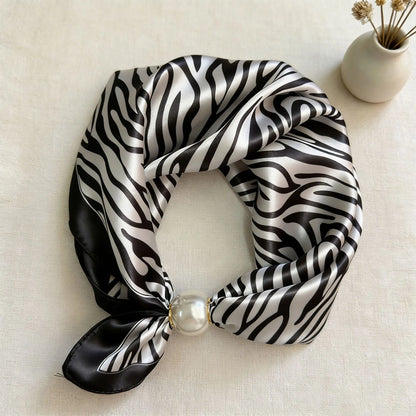 Slim printed faux silk neck scarf featuring a smooth satin finish, botanical-inspired print, and oversized pearl magnetic closure for a refined women's fashion accessory.