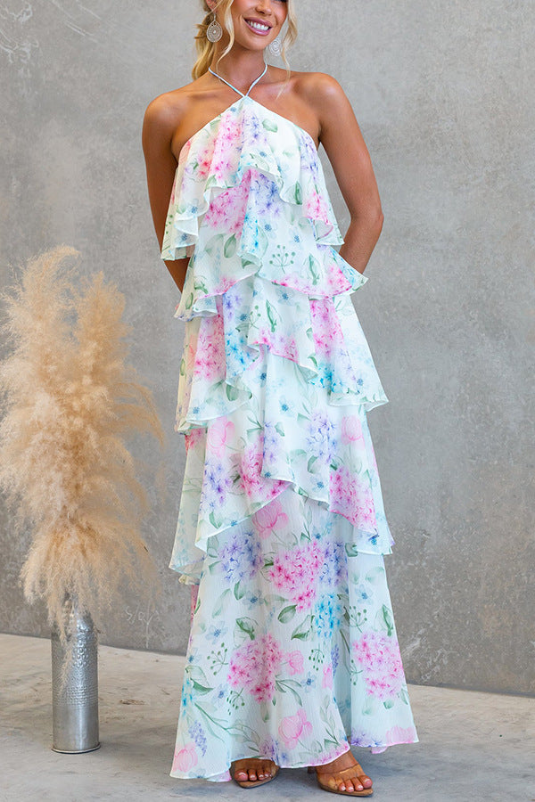 Tiered maxi dress with halter neckline and open-back detail, floral maxi dress featuring watercolor blooms and cascading ruffles, ideal floral wedding guest style and garden party maxi dress.