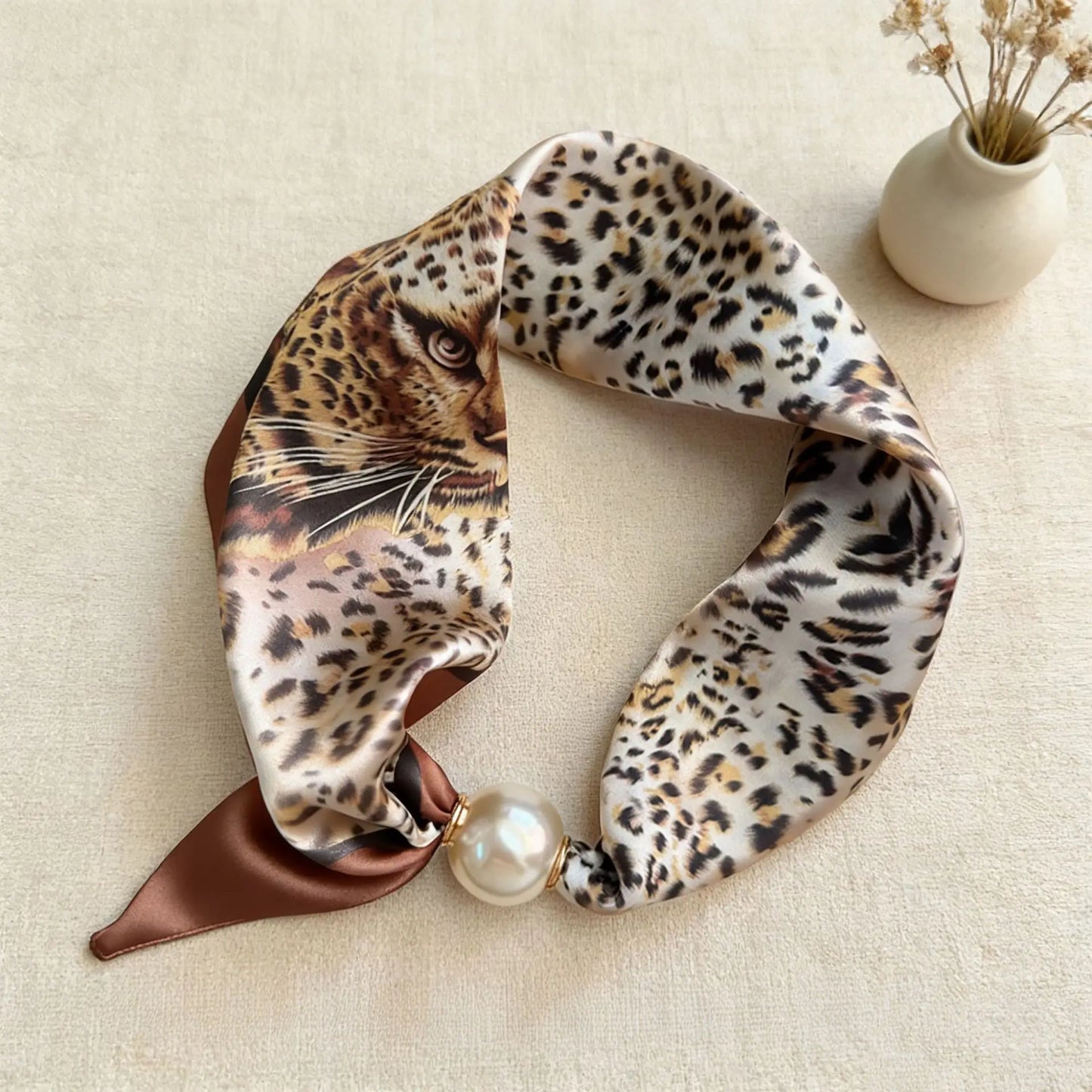 Slim printed faux silk neck scarf featuring a smooth satin finish, botanical-inspired print, and oversized pearl magnetic closure for a refined women's fashion accessory.