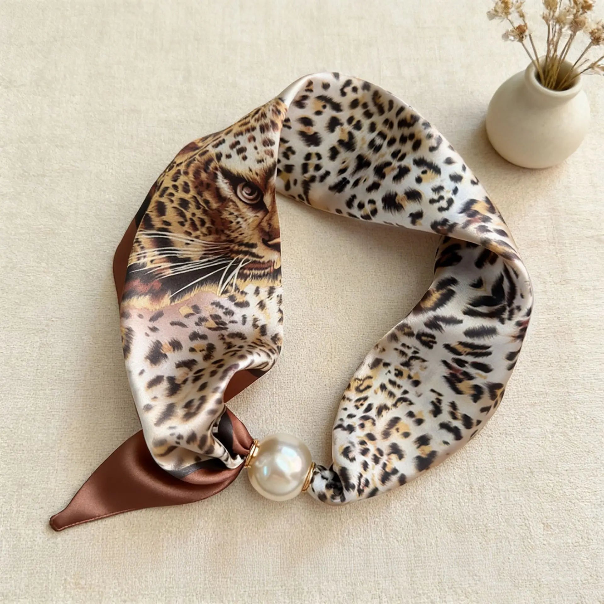 Slim printed faux silk neck scarf featuring a smooth satin finish, botanical-inspired print, and oversized pearl magnetic closure for a refined women's fashion accessory.