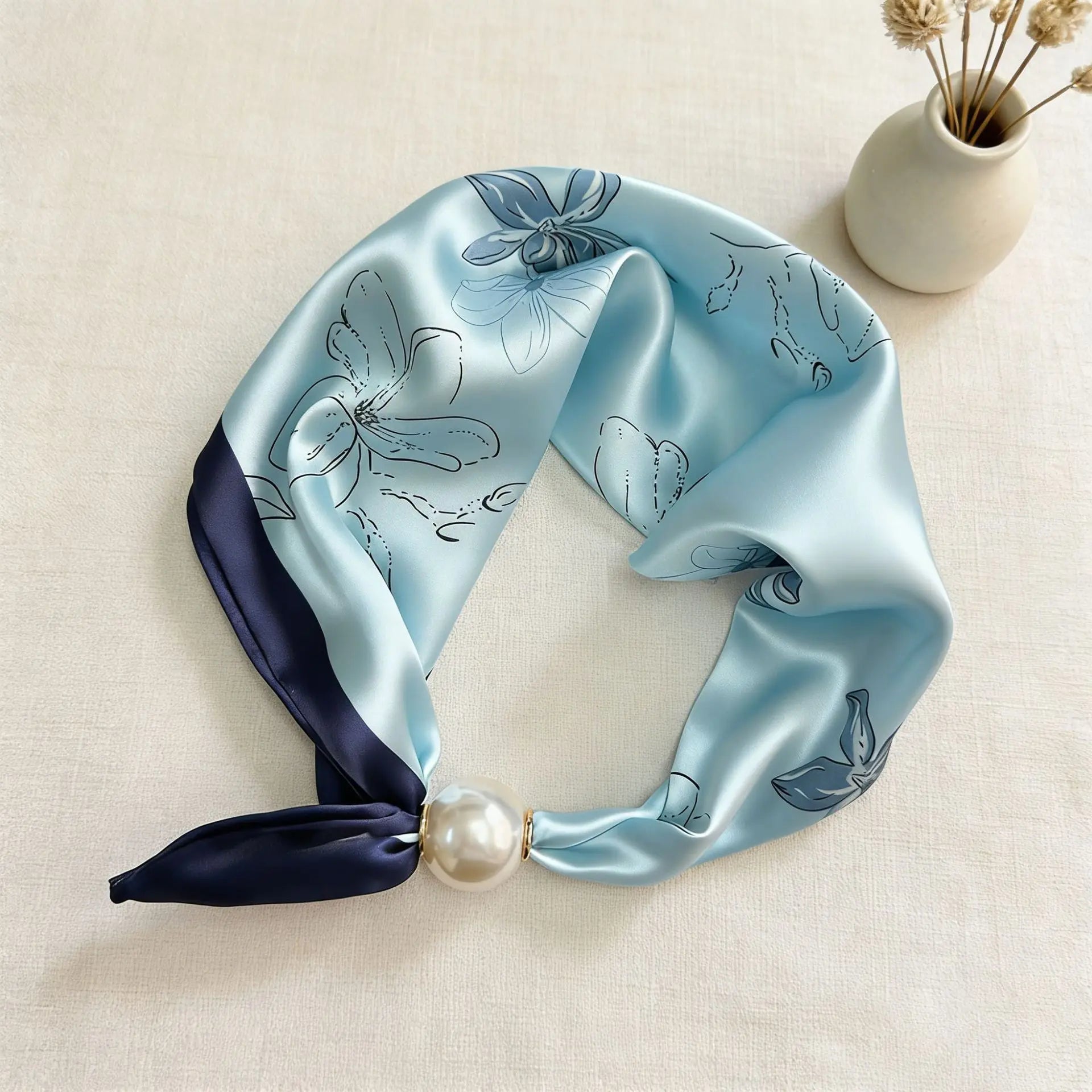 Slim printed faux silk neck scarf featuring a smooth satin finish, botanical-inspired print, and oversized pearl magnetic closure for a refined women's fashion accessory.