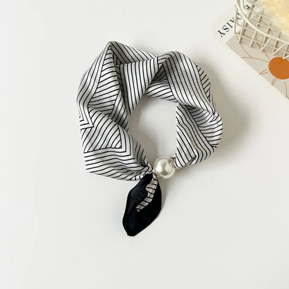 Slim printed faux silk neck scarf featuring a smooth satin finish, botanical-inspired print, and oversized pearl magnetic closure for a refined women's fashion accessory.