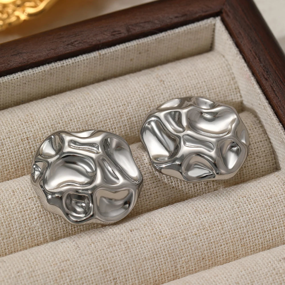 Textured metal statement stud earrings in silver, bold abstract design with high-shine finish, contemporary women’s fashion jewelry for workwear and special occasions.